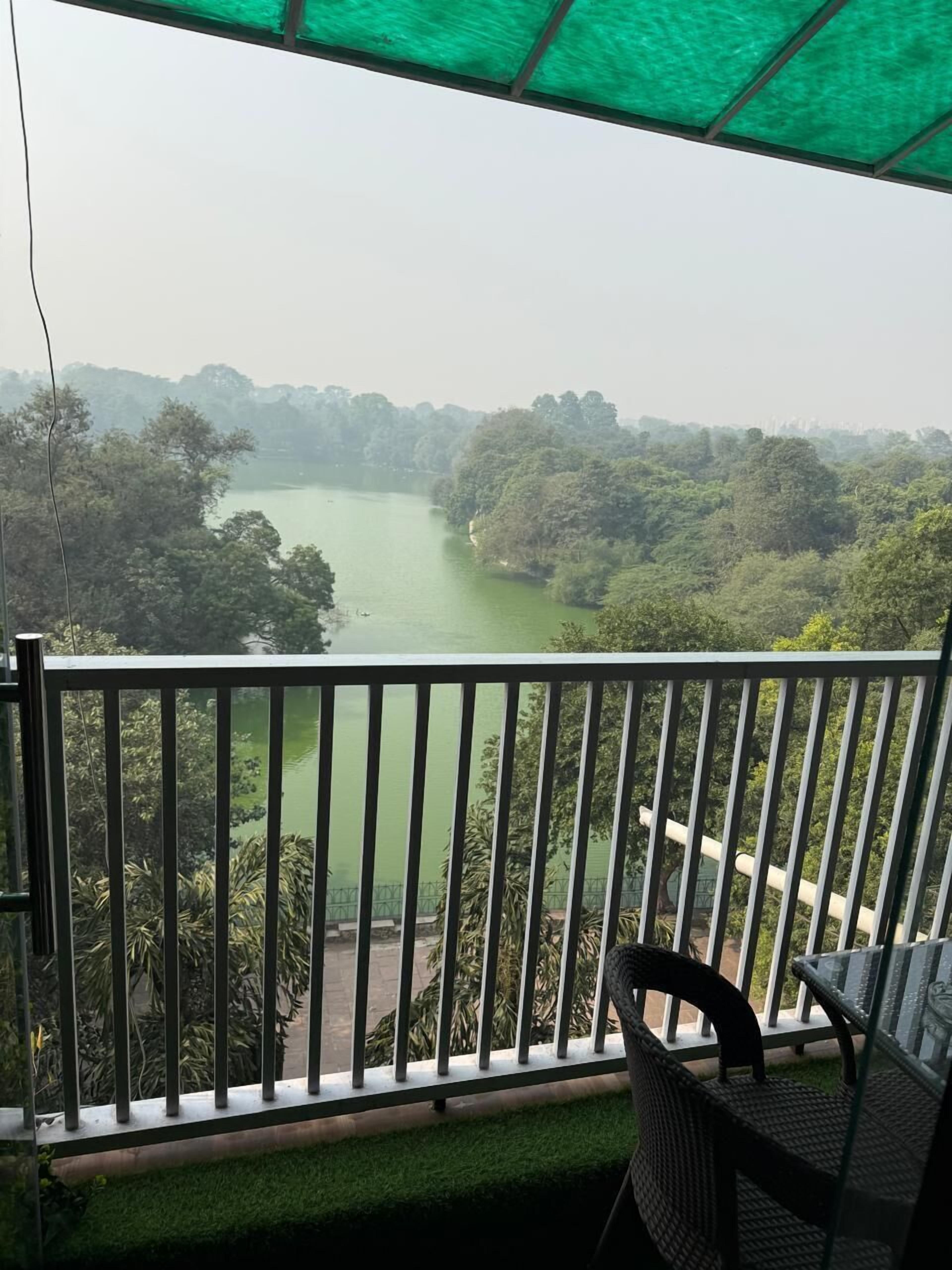 A balcony with a view of a river and dense greenery.