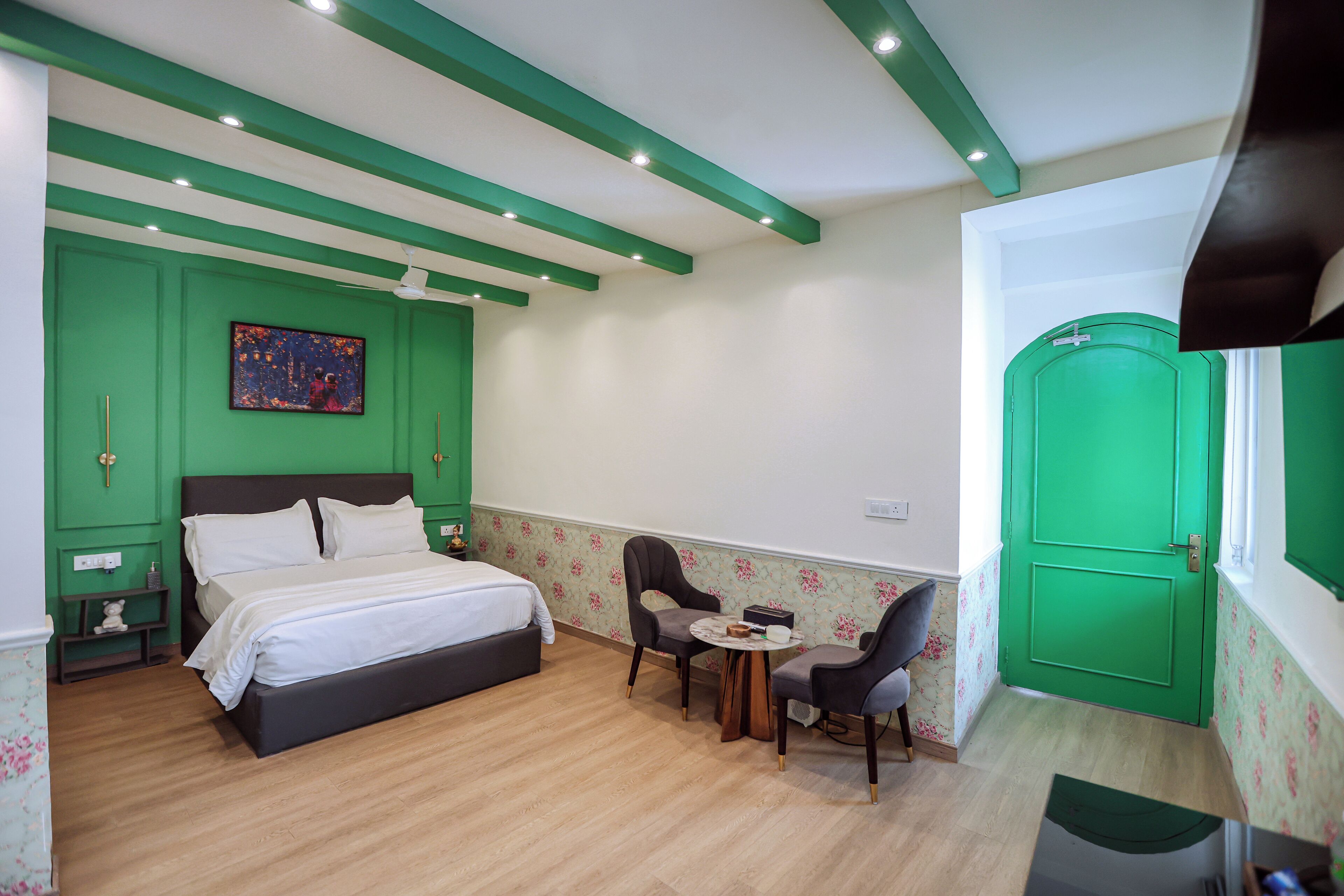 A bedroom with a bed, two chairs, a small table, and a green door.