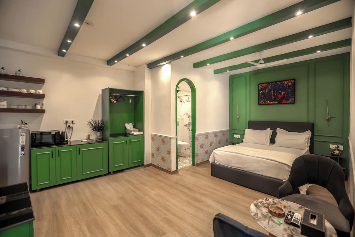 A modern bedroom with a bed, a desk, and a green wardrobe.