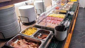 Un bufé con diversas opciones de comida, incluyendo carnes, quesos y frutas.
