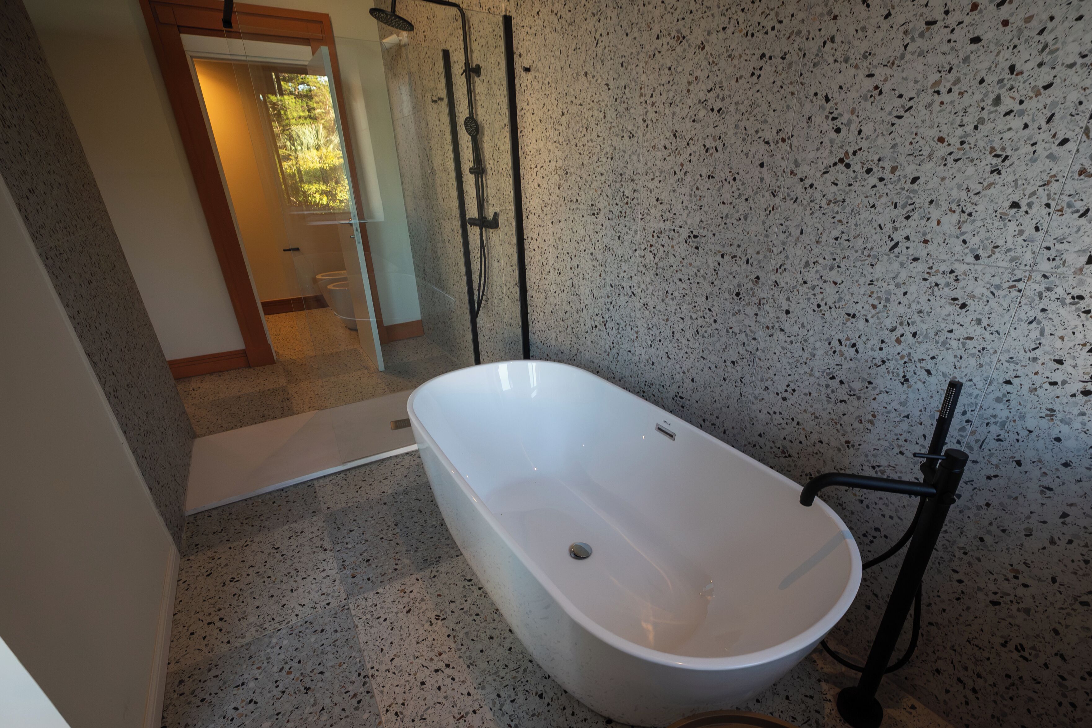 Een badkamer met een vrijstaand bad, een douche en een toilet met glazen cabine.