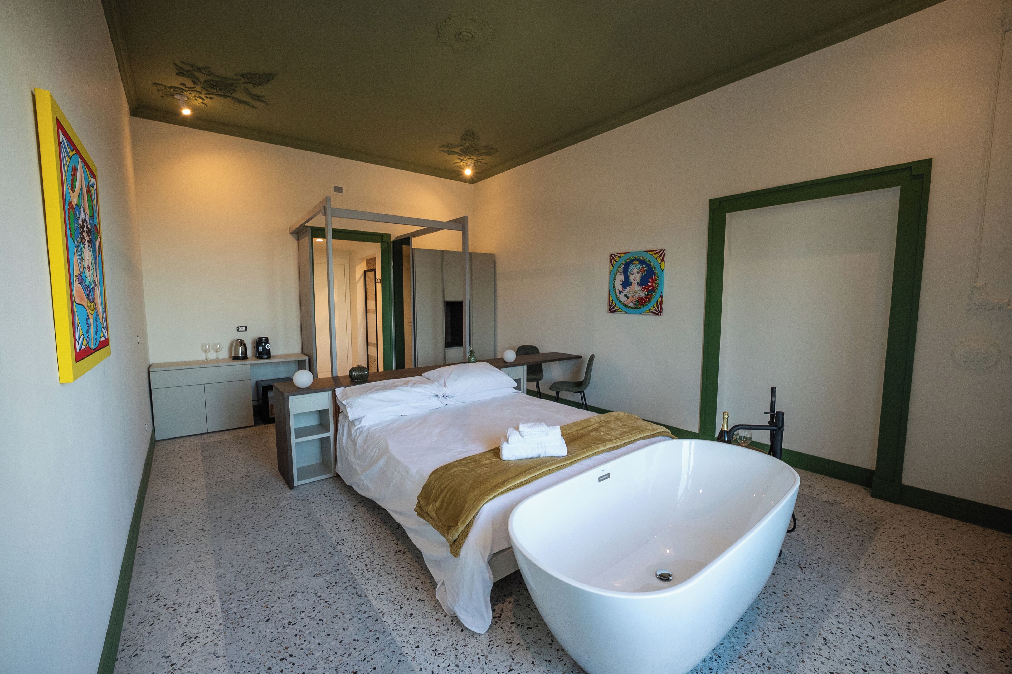 A bedroom with a large bed, a bathtub, a desk, and a chair.