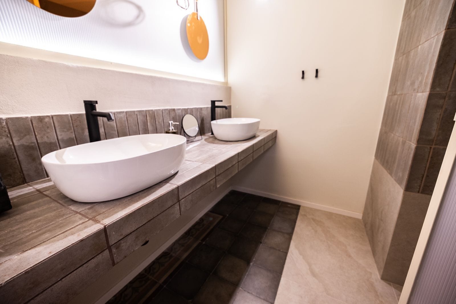 A bathroom with two white vessel sinks, a mirror, and a towel rack.