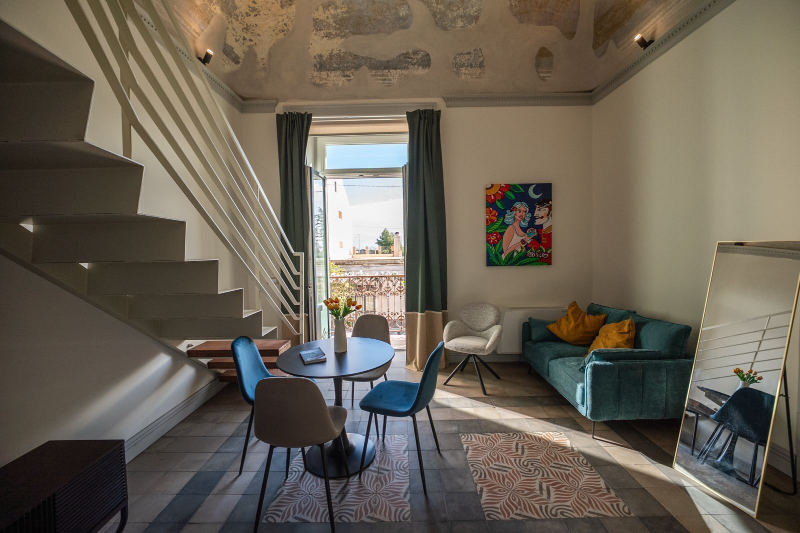 A modern living room with a staircase, a dining area, and a sofa.