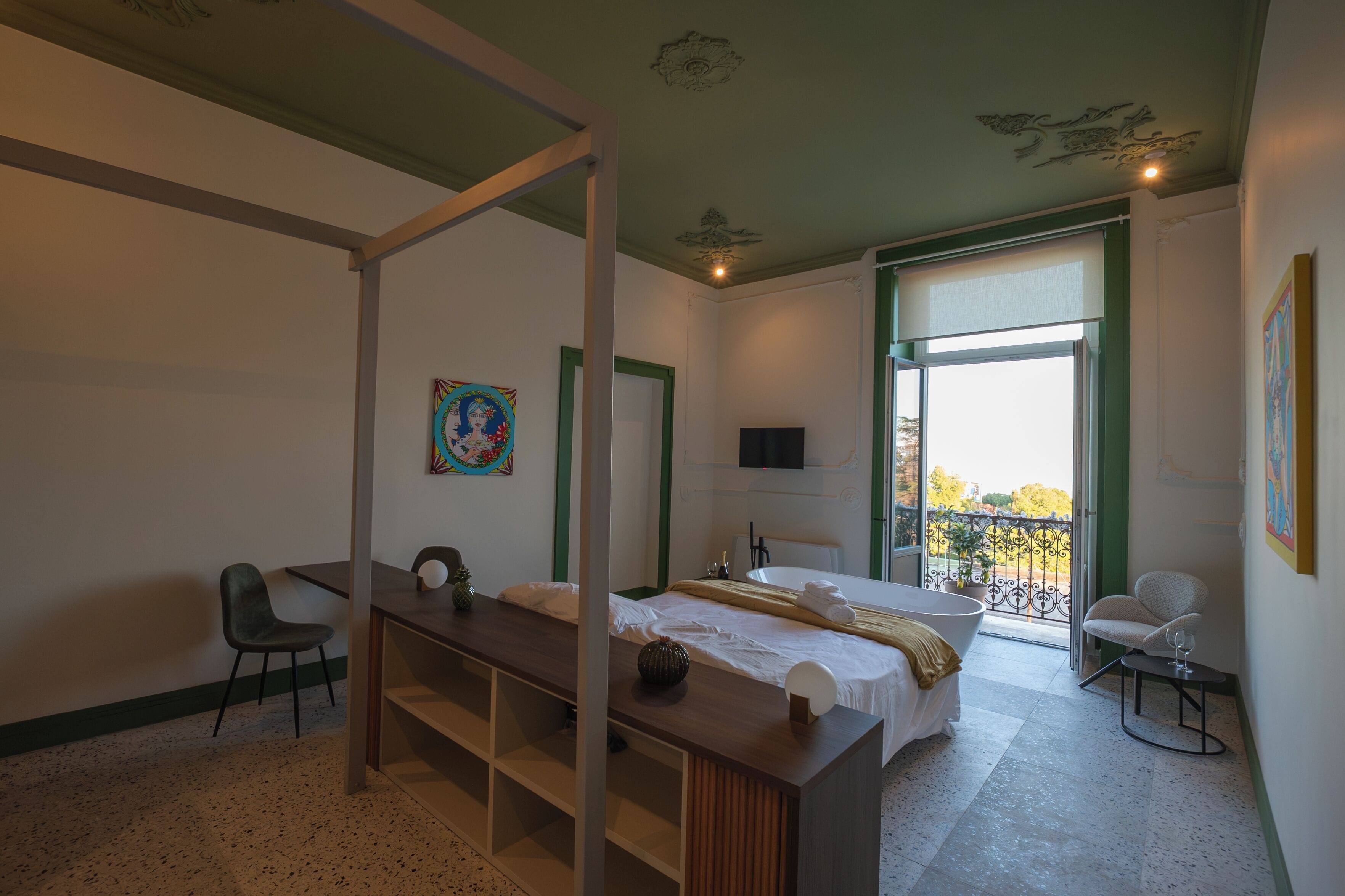 Un dormitorio con cama, escritorio, silla, ventana y balcón.