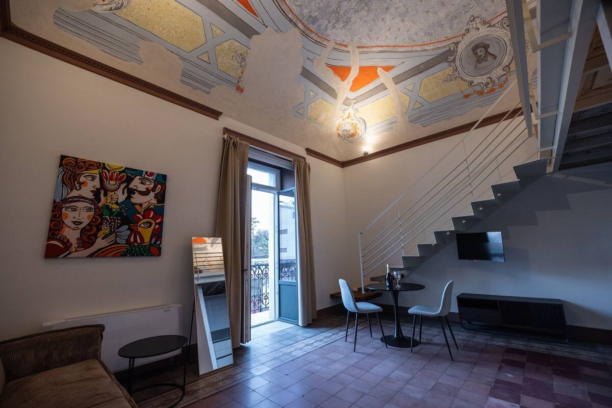 Ein modernes Interieur mit einer Treppe, einem Essbereich und einem farbenfrohen Gemälde an der Wand.