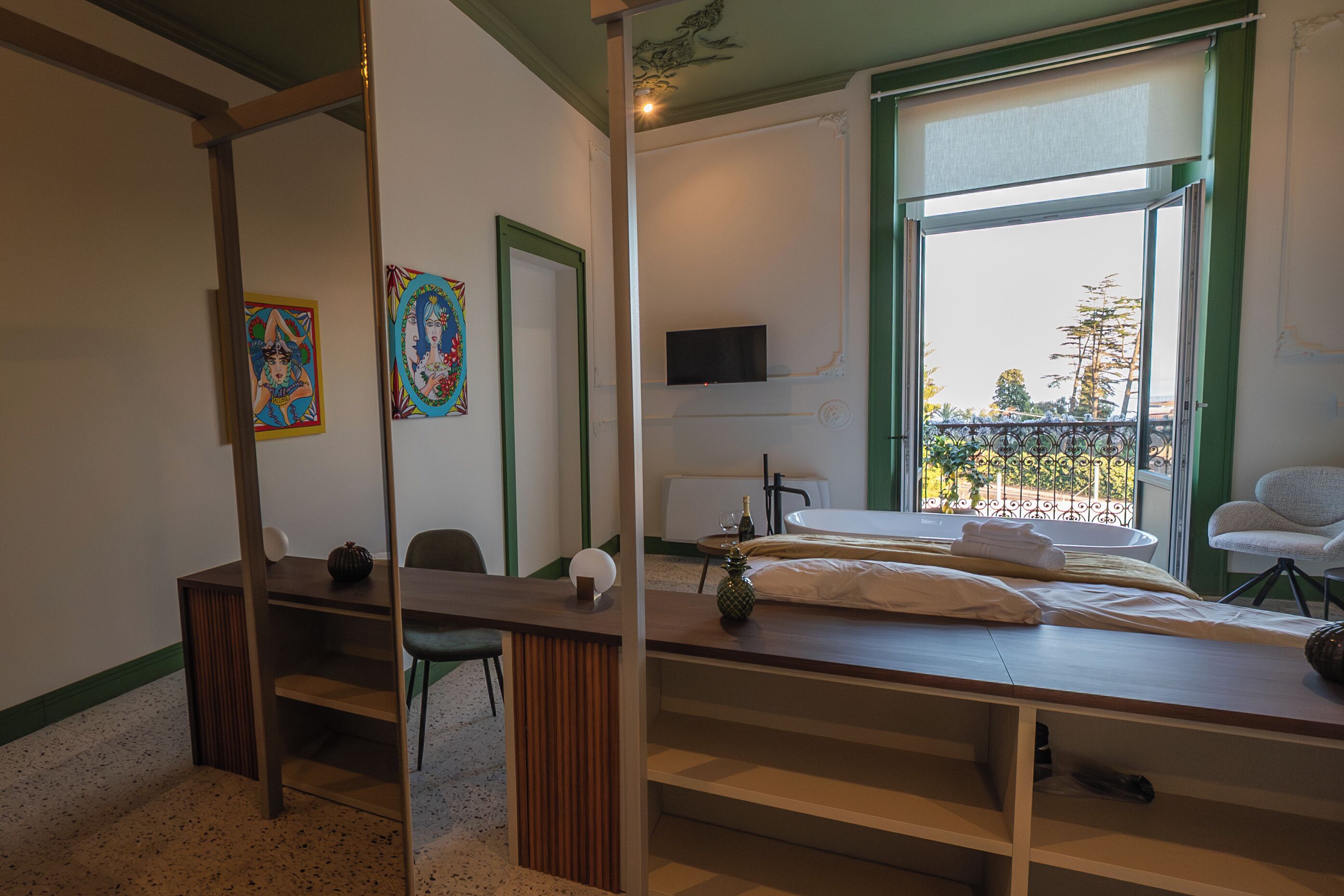 A hotel room with a bed, a desk, a chair, a TV, and a window with a view of the outside.