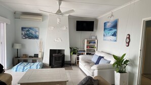 Una sala de estar con sofá, una mesa de centro, chimenea, televisor y estantería.