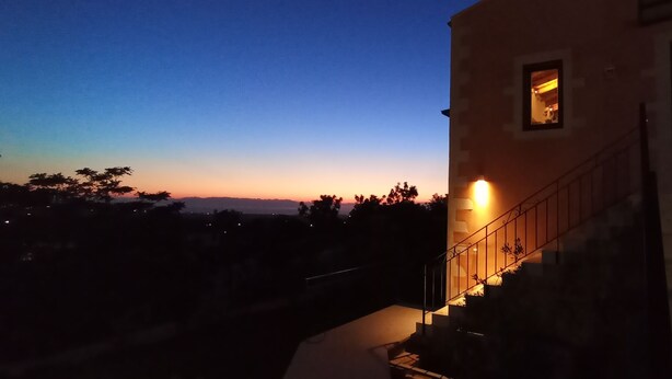 En bygning med en trappe op til en etage, et lille vindue og udsigt til himlen i solnedgang.