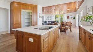 Uma cozinha ampla com armários de madeira, uma ilha central e um espaço de refeições com cadeiras e mesa de madeira.