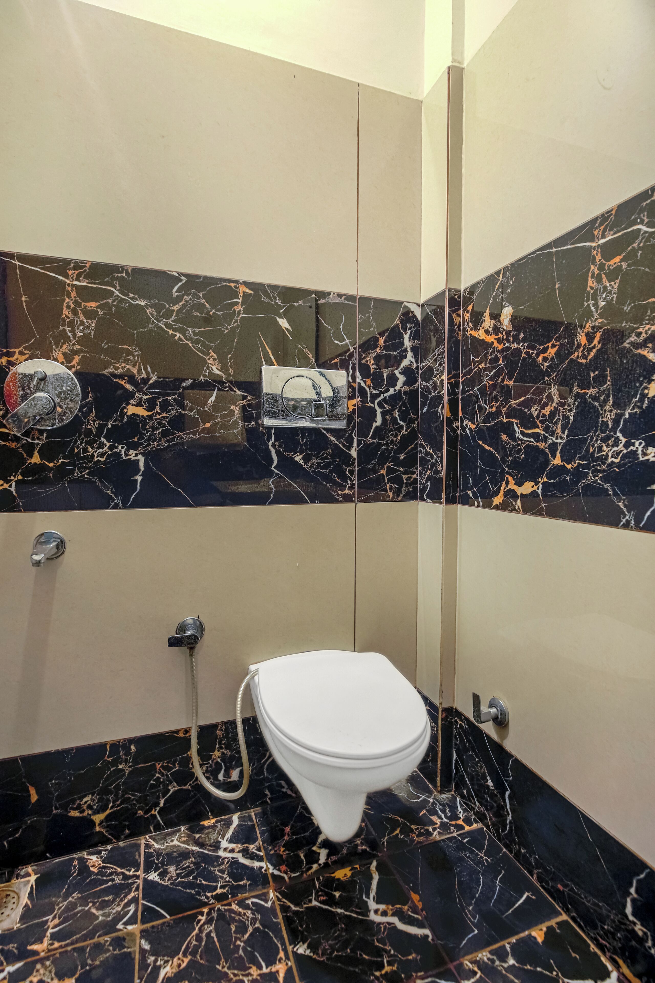 A bathroom with a white toilet, a shower, and a marble-tiled floor and walls.