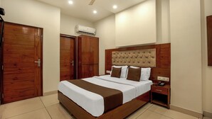 A bedroom with a wooden bed, a nightstand, a wardrobe, and an air conditioning unit. -  Hotel RK Residency Opposite ISBT Sector 43 Chandigarh (Chandigarh)