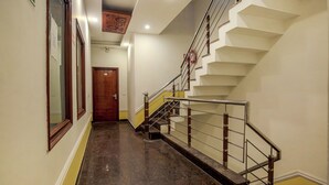 A hallway with a marble floor, a wooden door at the end, and a staircase with metal railings and wooden steps. -  Hotel RK Residency Opposite ISBT Sector 43 Chandigarh (Chandigarh)