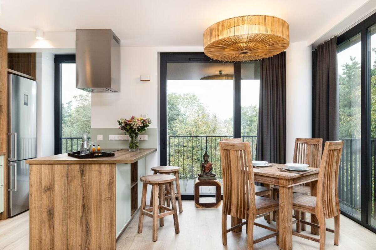 A modern kitchen with a wooden island, bar stools, and a dining table with chairs.