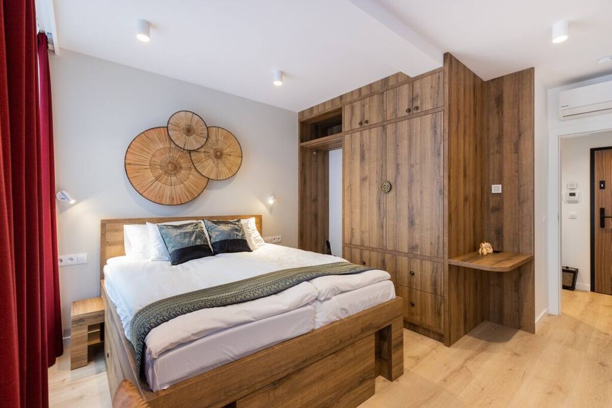 A bedroom with a wooden bed, a large wardrobe, and a wall-mounted circular artwork.