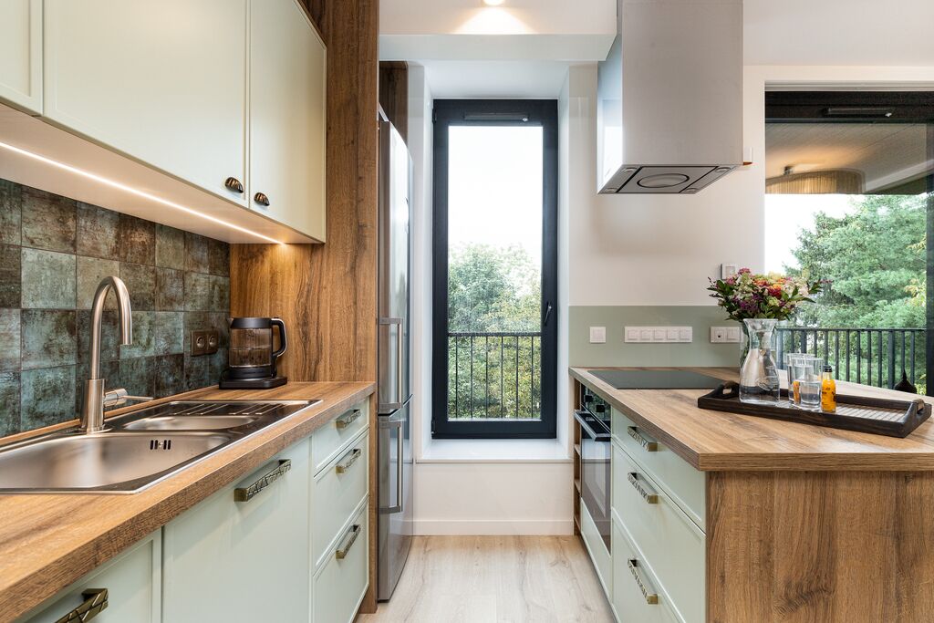 A modern kitchen with a large window, stainless steel appliances, and a wooden countertop.