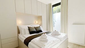 A modern hotel room with a large bed, built-in wardrobe, and a window with curtains. - Araliya (Kraków)