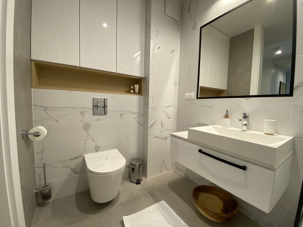 Un baño moderno con inodoro, lavamanos y espejo.
