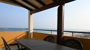 Et træbord og stole på en balkon med udsigt over havet.