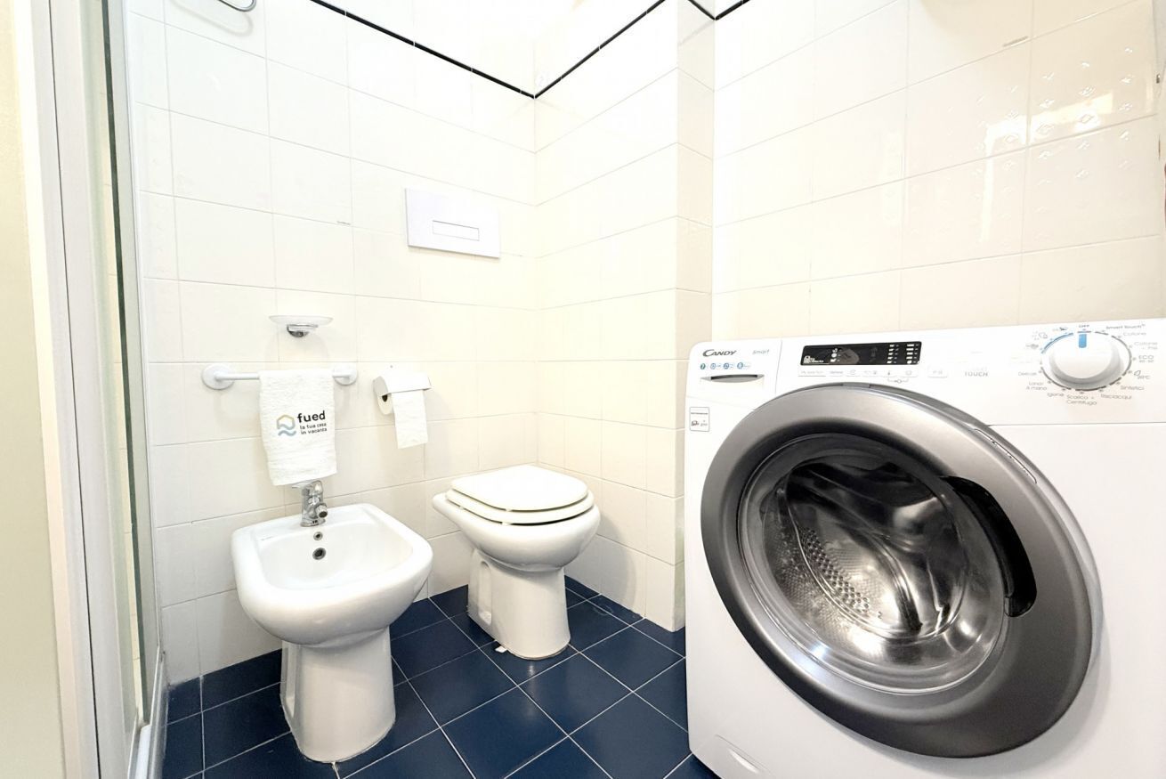 Een kleine badkamer met een toilet, een bidet en een voorlader wasmachine.