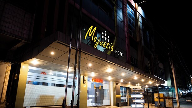 The exterior of Majestic Hotel with a glass facade, illuminated entrance, and a signboard. - Tripletree Majestiq Hotel (Pekanbaru)