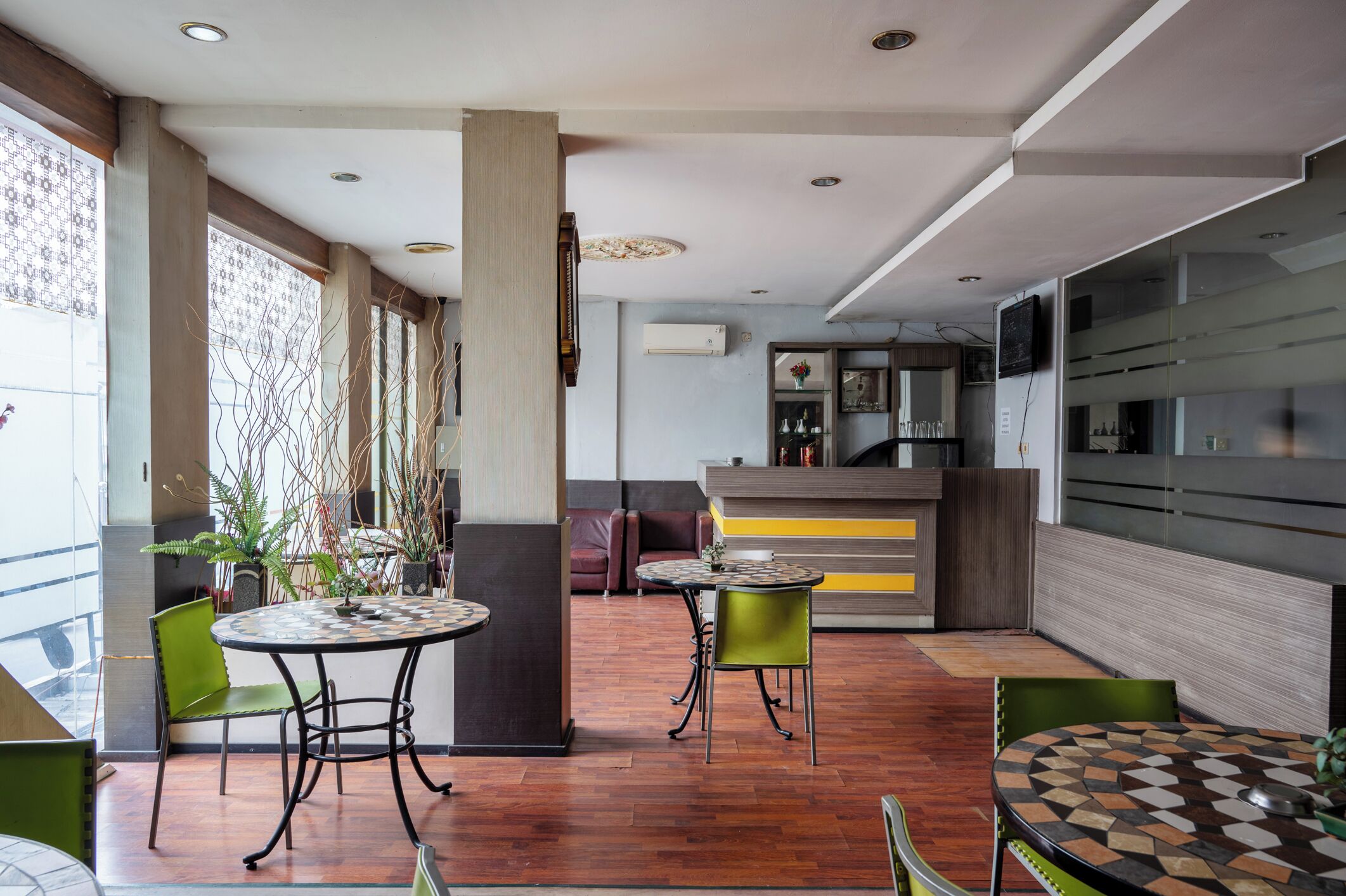 Decoração moderna com balcão de recepção, área de estar e cozinha ao fundo.