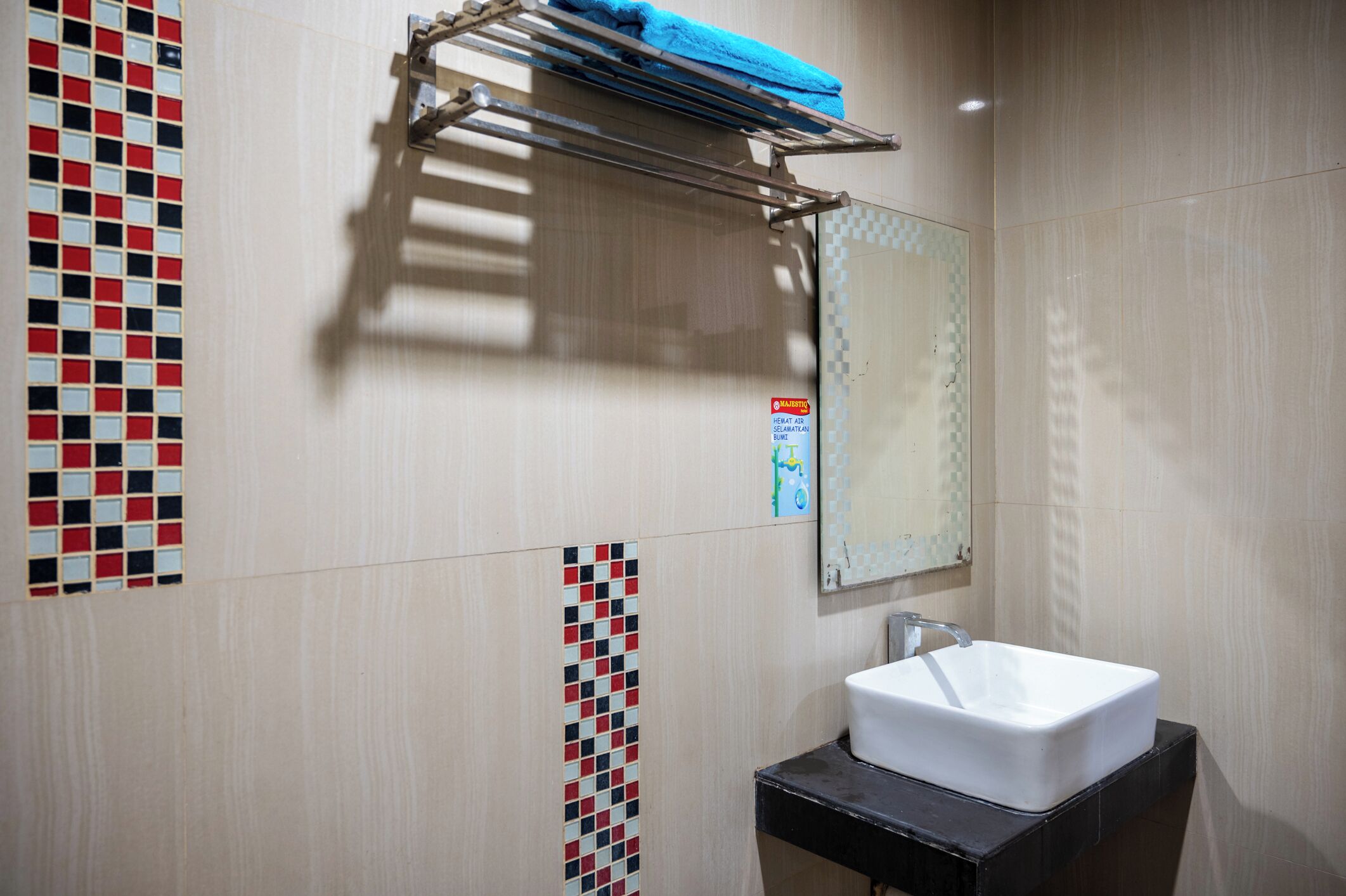 Een badkamer met een wit wastafelmeubel, een handdoekhouder met een blauwe handdoek en decoratieve betegelde muren.