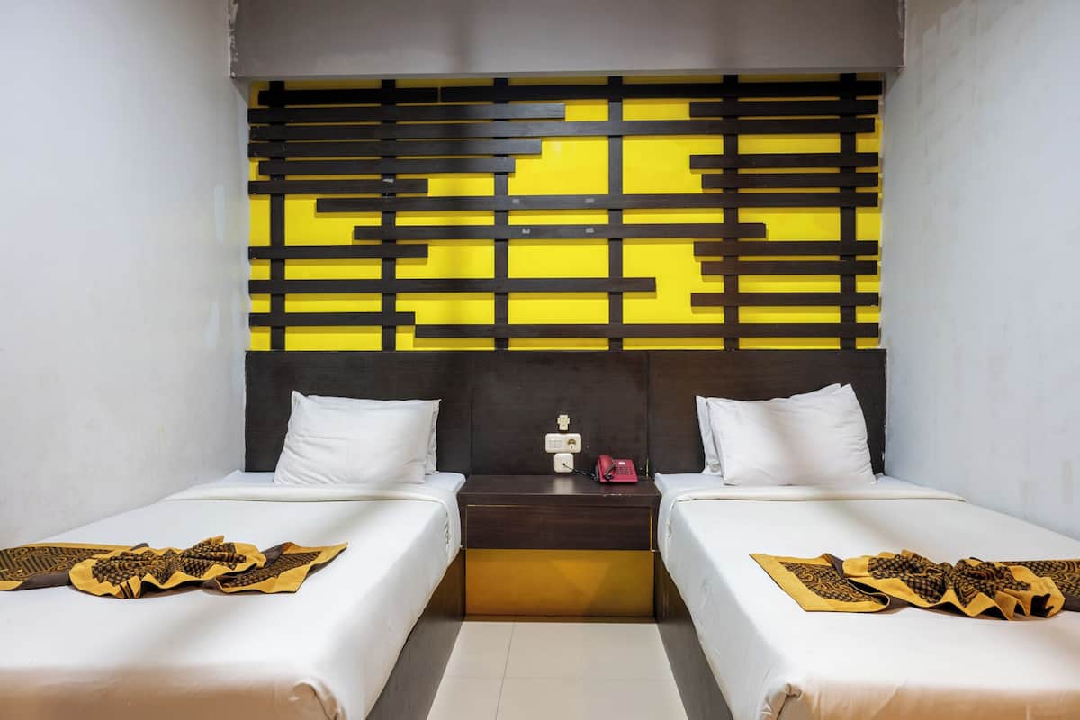 Habitación de hotel con dos camas, cabecera oscura y un panel decorativo en la pared.