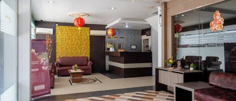 A hotel lobby with a reception desk, seating area, and decorative elements.