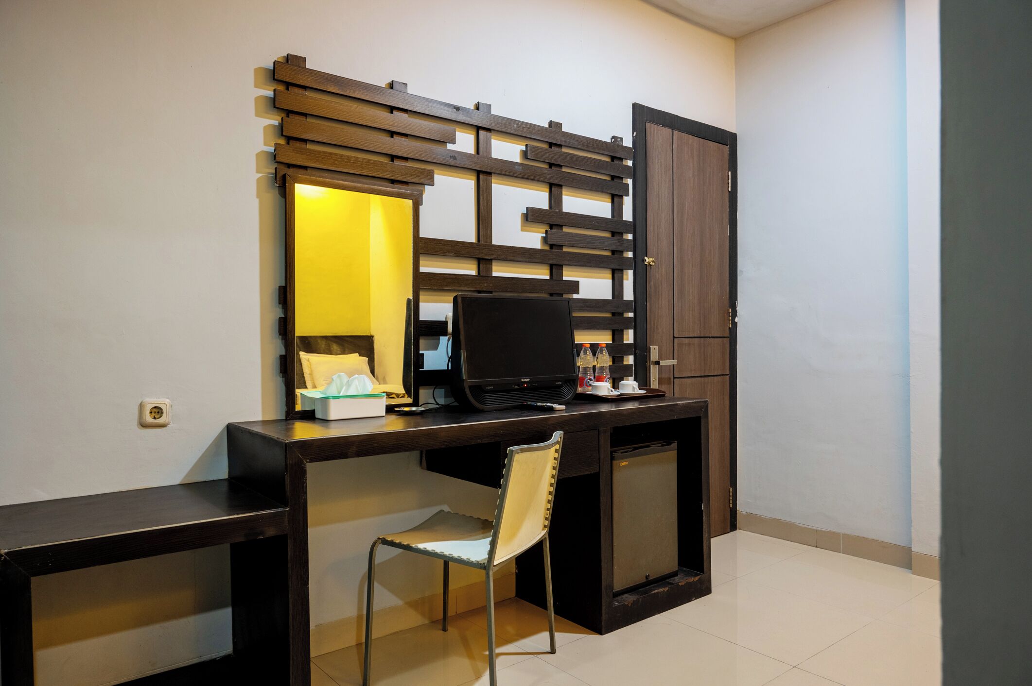 Un espace de travail compact comprenant un bureau, une chaise, un téléviseur et un meuble de rangement.