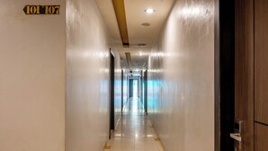 A long, narrow hallway with a tiled floor and a door on the right. - Tripletree Majestiq Hotel (Pekanbaru)