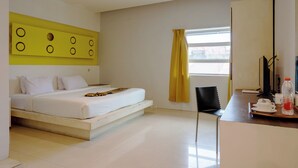 A modern hotel room with a bed, a desk, a chair, and a window with yellow curtains. - Tripletree Majestiq Hotel (Pekanbaru)