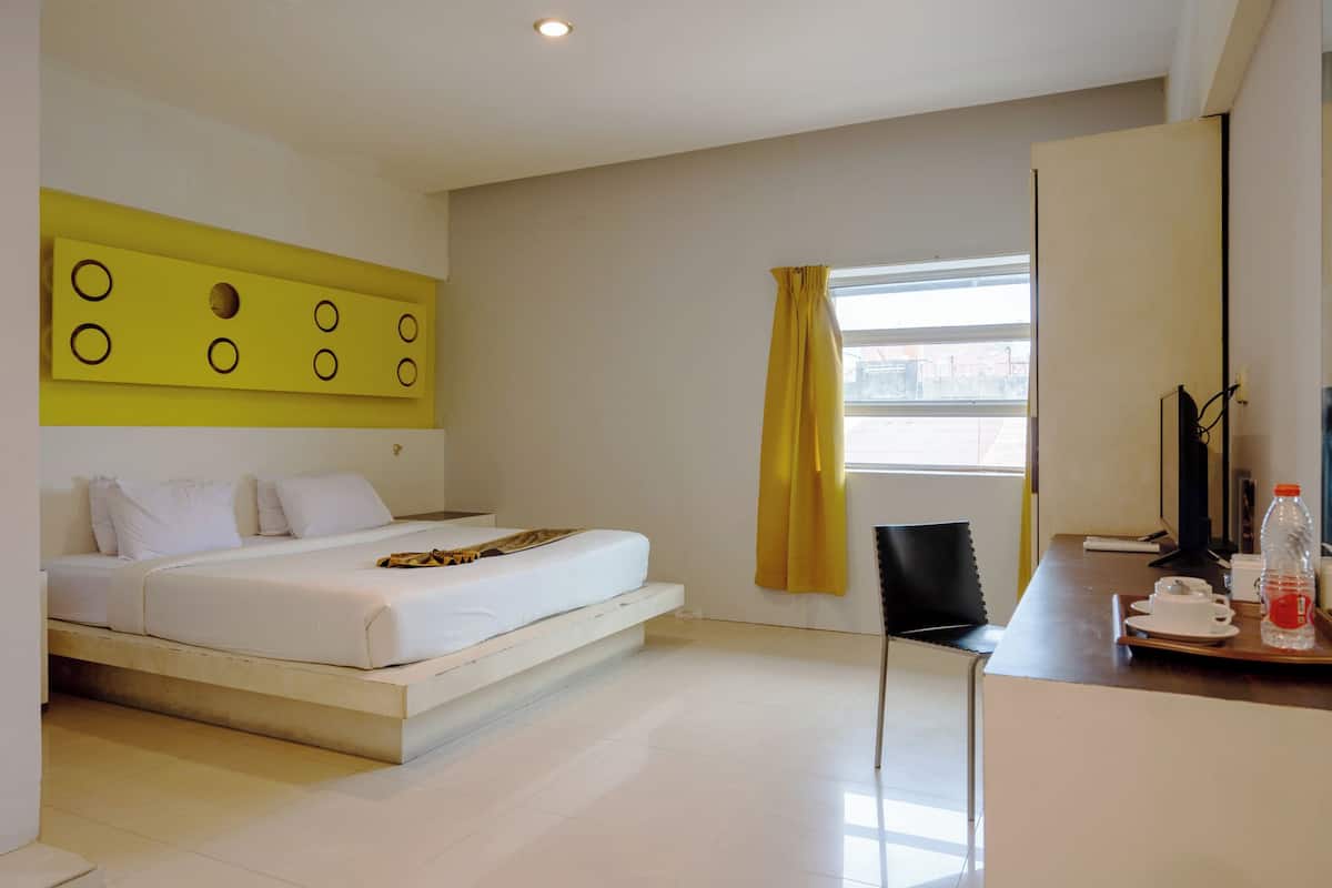 Una habitación de hotel moderna con una cama, un escritorio, una silla y una ventana con cortinas amarillas.