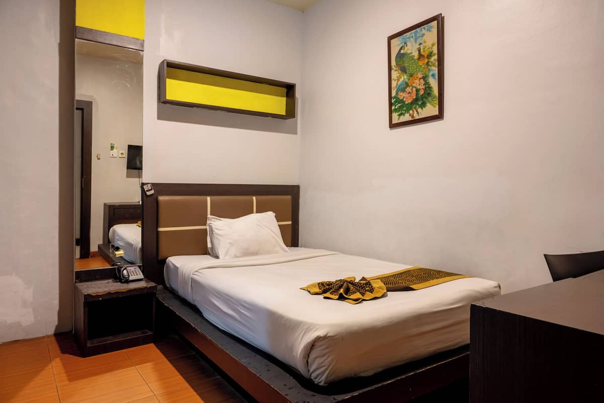Una habitación de hotel con cama, mesita de noche y un cuadro en la pared.