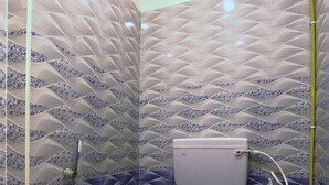 A bathroom with a patterned tile design, a toilet, and a shower area. - BLESSINGS SELECT PERIAMET (Chennai)