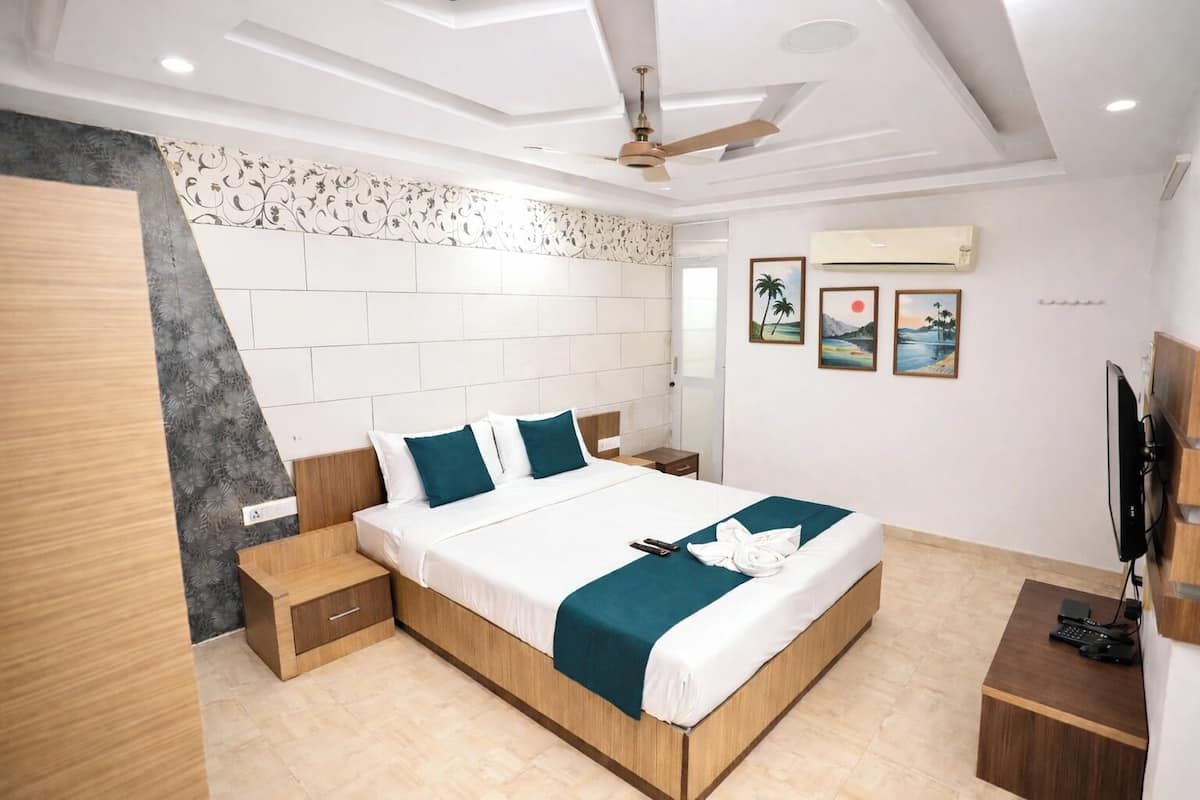 Une chambre d’hôtel moderne avec un grand lit, une tête de lit en bois et un téléviseur à écran plat.