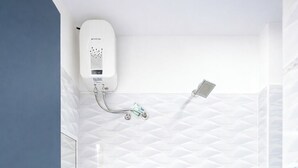 A bathroom with a white sink, a handheld showerhead, and a wall-mounted heater. - BLESSINGS SELECT PERIAMET (Chennai)