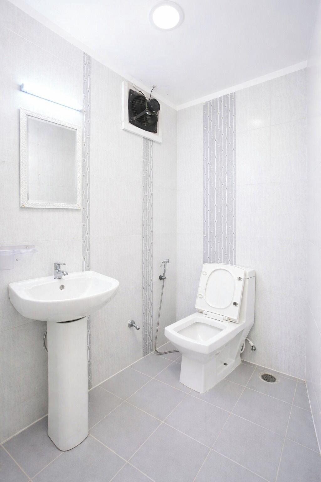 Um banheiro com pia de pedestal, vaso sanitário e espelho.