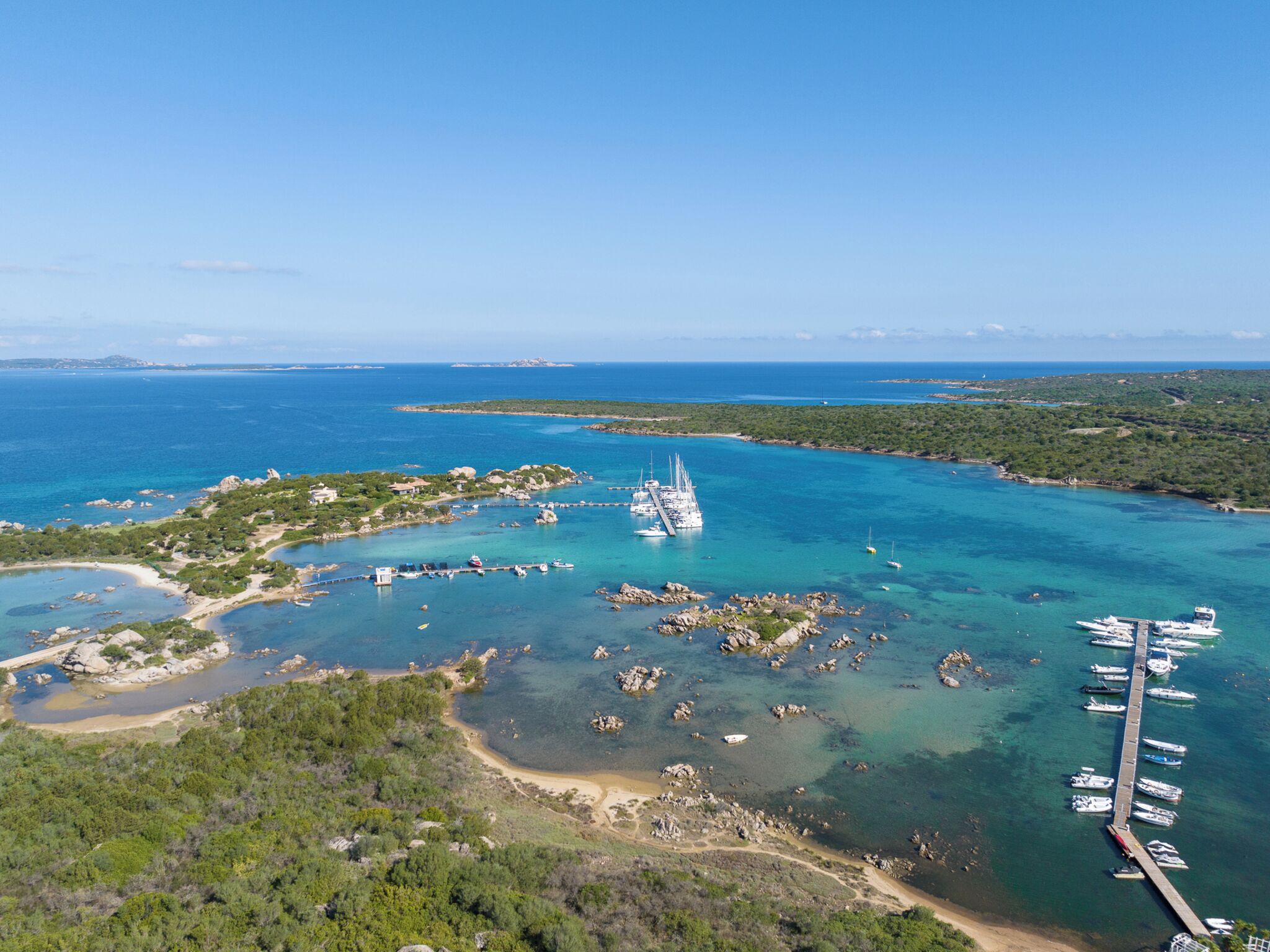 An aerial view of a coastal area with a marina, boats, and rocky terrain.