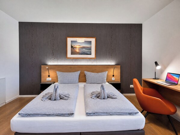 Ein modernes Hotelzimmer mit Bett, Schreibtisch, Stuhl und einem Bild an der Wand.