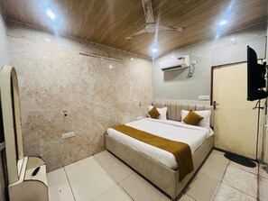 Une chambre d’hôtel avec un lit, un ventilateur de plafond, un appareil de climatisation et une porte.
