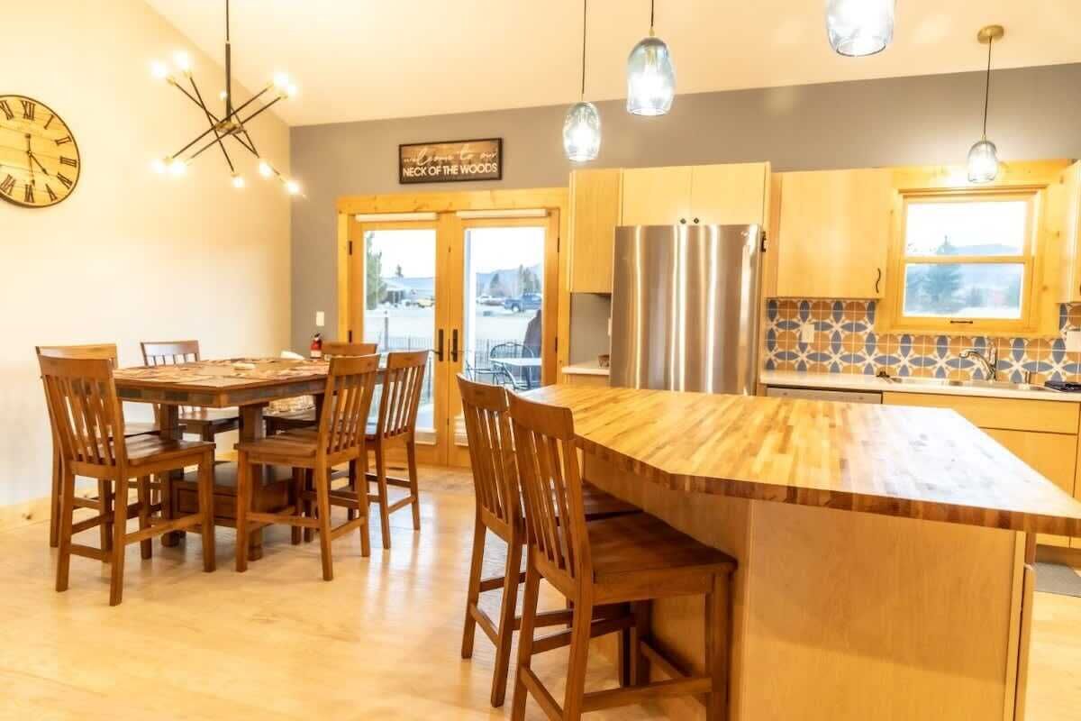 A modern kitchen with wooden cabinets, a stainless steel refrigerator, and a large island with chairs.