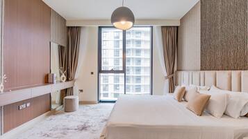 Une chambre d’hôtel moderne avec un grand lit, une coiffeuse avec un miroir, un luminaire suspendu et une vue sur la ville par la fenêtre.
