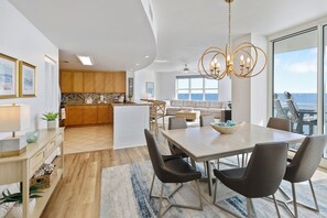Un salón espacioso con mesa de comedor, muebles modernos y vista al océano.