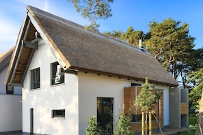 A modern house with a sloped roof, large windows, and a wooden facade. - Exclusive 5-star vacation home with sauna, whirlpool and garden in Karlshagen (Karlshagen)