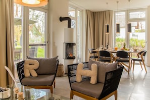 A modern living room with a fireplace, comfortable seating, and a dining area with a view of the garden. - Exclusive 5-star vacation home with a sauna, hot tub, and garden in Karlshagen (Karlshagen)