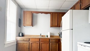 Een keuken met houten kastjes, een witte koelkast en een houten aanrecht.