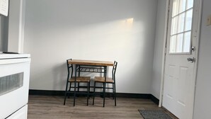 Een kamer met een houten tafel, twee stoelen, een witte deur en een raam.