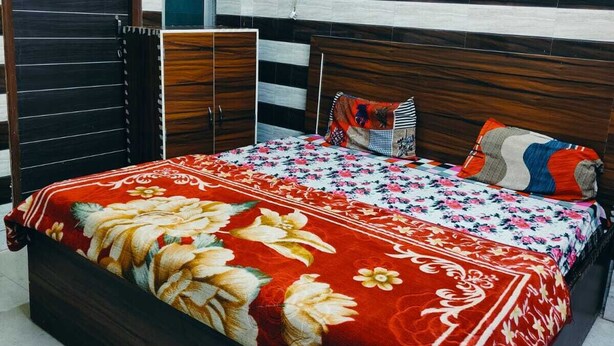 Ein Schlafzimmer mit Bett, Kleiderschrank, Heizkörper und Fenster.