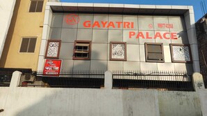 Ein Gebäude mit einem Schild für Gayatri Palace, das eine moderne Fassade mit geometrischen Mustern und einer Kontaktnummer zeigt.